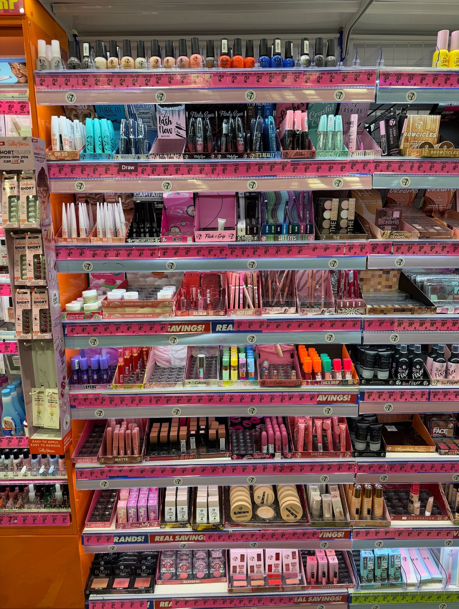 A densely stocked cosmetics bay with product facings and shelf-edge labels